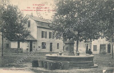 Carte postale ancienne La Fontaine du Foirail et la Poste — Saint-Geniez-d'Olt (Aveyron)