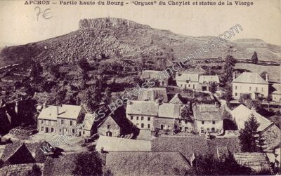 Carte postale ancienne Partie haute du Bourg - "Orgues" du Cheylet et statue de la Vierge — Apchon (Cantal)