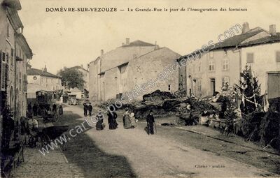 Carte postale ancienne La Grande-Rue le jour de l'inauguration des fontaines — Domèvre-sur-Vezouze (Meurthe-et-Moselle)